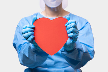 Doctor wearing protective equipment (PPE) , Hand of doctor in blue medical gloves show red paper heart.