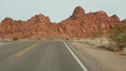 Road trip, driving auto in Valley of Fire, Las Vegas, Nevada, USA. Hitchhiking traveling in America, highway journey. Red alien rock formation, Mojave desert wilderness looks like Mars. View from car.