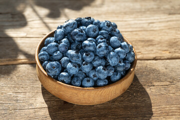 Blueberries in a round wooden plate close-up. Blueberries on a wooden background. Healthy food. Harvest on the table. Rustic kitchen table