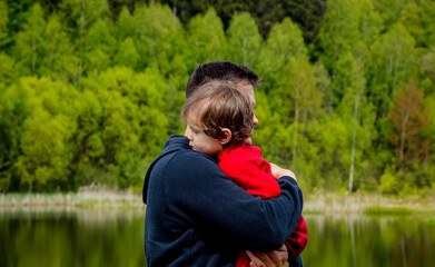 Fototapeta na wymiar father hugs his son by the lake in the forest
