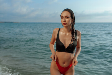 Wet sexy girl in a swimsuit comes out of the sea