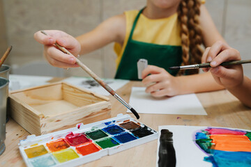 Cropped image of kids painting with watercolor. Low angle.