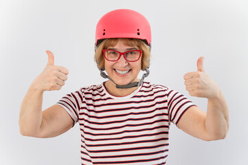 Elderly woman in ski helmet showing thumb up on white background.
