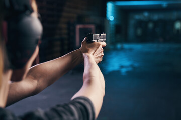 Shooter practicing a two-handed hold at a shooting range - obrazy, fototapety, plakaty