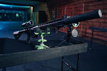 Long-barreled assault gun with a riflescope arranged on the desk