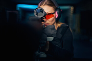 Fototapeta na wymiar Focused young woman shooting a modern firearm