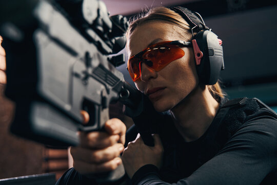 Female shooter in safety goggles firing a weapon