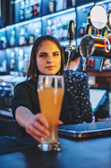 woman bartender hand at beer tap pouring a draught beer in glass serving in a restaurant or pub