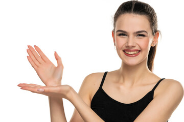 Fototapeta premium A young beautiful smiling woman with tied hair advertises an imaginary produc