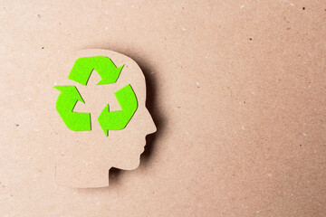 Head profile silhouette with recycle symbol on brown paper background. Ecology thinking.