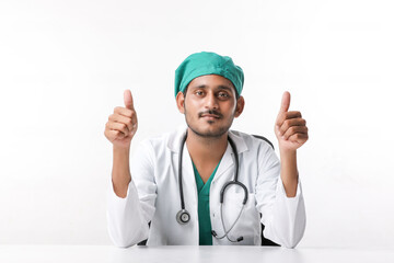 Doctor in a white coat with a stethoscope and showing thumbs up over white background.