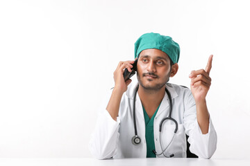 Young indian male doctor talking on smartphone at clinic.