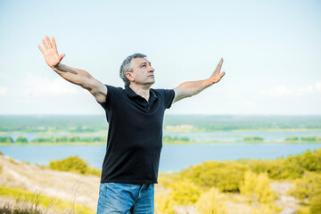 Mature man feels freedom of life against the backdrop of hills. Senior man felling 