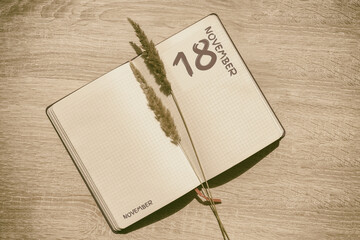 november 18. 18th day of month, calendar date.Blank pages of notebook are beige, with dried...