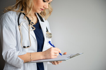.Soft focus medical female doctor or nurse writting a patient medical chart isolated on gray in hospital with copyspace