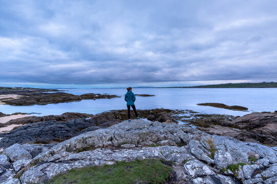 Caucasian female traveler standing on stones admiring the landscape on cloudy day