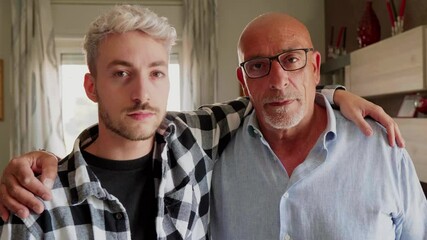 Father and son standing at home with arms around