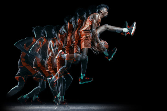 Young african man, basketball player in motion with ball isolated over black background. Stroboscopic effect