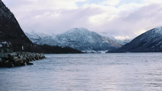 A beautiful view of the sea and snowy mountains in Volda, Norway