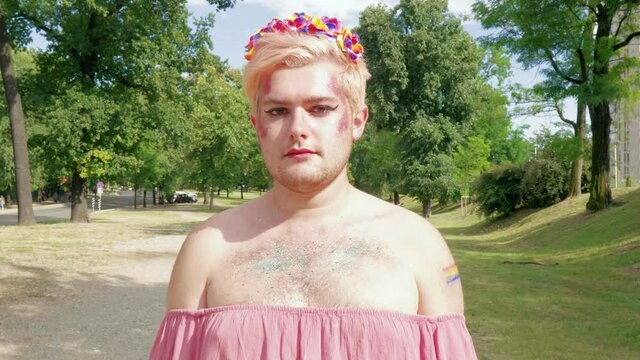 Blond mamn with rainbow-colored flowers in hair standing park
