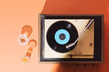 Flat lay gramophone record player from sixties. Turntable for single vinyl on orange background. ...