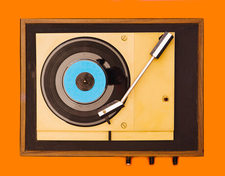 Flat lay gramophone record player from sixties. Turntable for single vinyl on orange background.