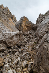 High mountain scenery with big stones, dolomitian peaks and cloudy sky in Dolomites