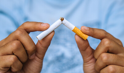 Cigarette.World No Tobacco Day Concept.Stop smoking cigarettes concept. Closeup woman holding broken cigarette in hands.