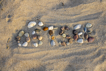 The german word Ostsee - baltic sea made with pebbles in the sand at sunset