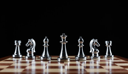Silvery chess figures standing on chessboard