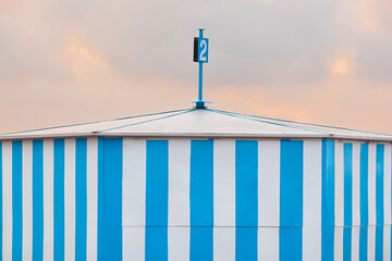 Blue striped beach hut at sunset. Summer time. Tourism