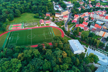 Aerial view of football and soccer field. Stadium with treadmill in residential city