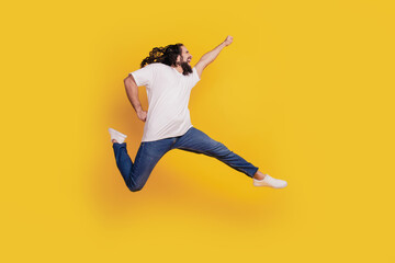 Fototapeta na wymiar Profile portrait of inspired positive crazy guy run fast jump hero move on yellow background
