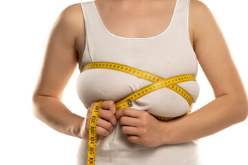 a woman measures with a measuring tape her large breasts