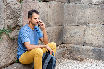 Young latin man with mobile phone sitting outside