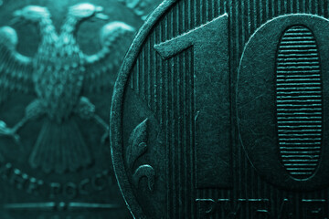 Russian coins of 10 rubles on both sides close-up. Dark dramatic background or wallpaper in turquoise color. Textured scratched coins from circulation. Economics, finance, banking in Russia. Macro