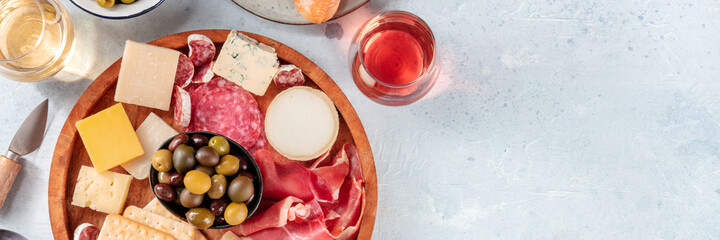 Charcuterie and cheese platter with wine panorama, shot from the top with a place for text. Italian antipasti for a restaurant menu header. Rose wine, blue and goat cheese etc