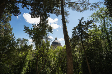 View of the top of a church and trees and clouds in Todi