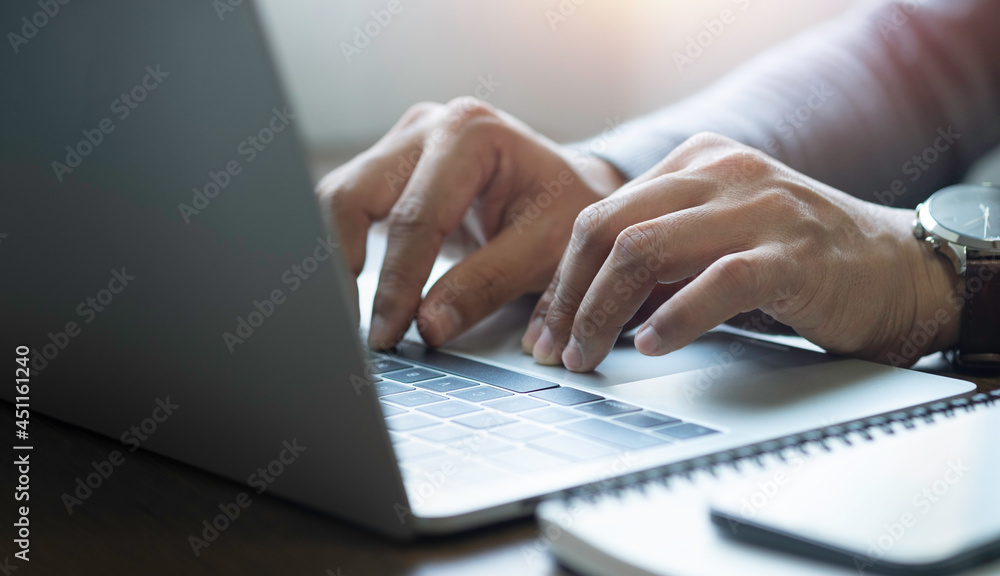 Poster close-up of man hands using and typing keyboard of laptop computer on office desk. workspace, busine