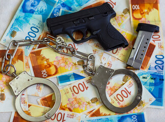 Steel police handcuffs, 9mm pistol gun, bullets on background of Israeli New Shekel banknotes with...