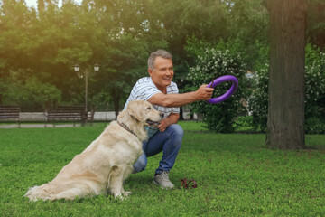 Happy senior man playing with his Golden Retriever dog in park