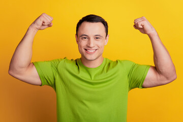 Portrait of strong guy show big biceps muscle sport concept on yellow background