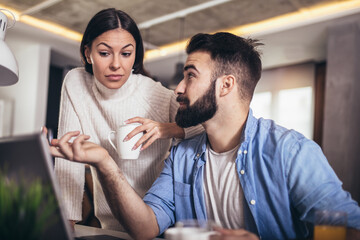 Young couple using a laptop and digital tablet together working at home