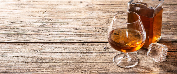 Cognac or whiskey drink on rustic wooden table and black background. Copy space. Panorama view