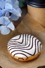 Donut and craft glass with drink on wooden table outdoors