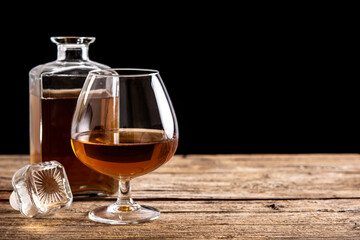 Cognac or whiskey drink on rustic wooden table and black background. Copy space	