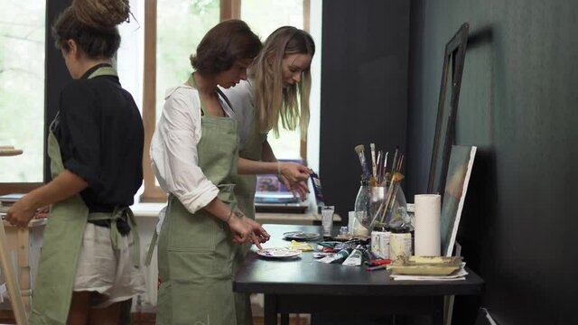 Women pours diverse paint into a palette on workshop