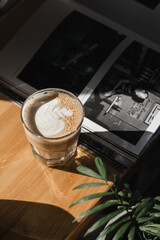 
A mug of hot coffee in female hands in the sunbeams on the background of a magazine in a cafe