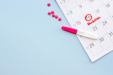 Ovulation home test and pills on calendarwith red mark