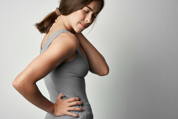 woman in gray t-shirt holding her back health problem rheumatism medicine